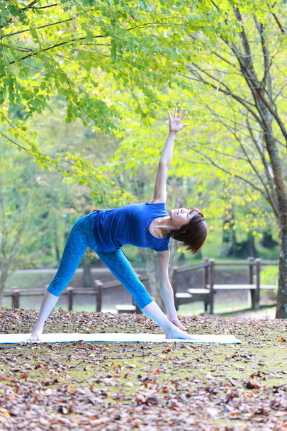 Japanese woman outside doing yoga triangle pose - Foto, imagen