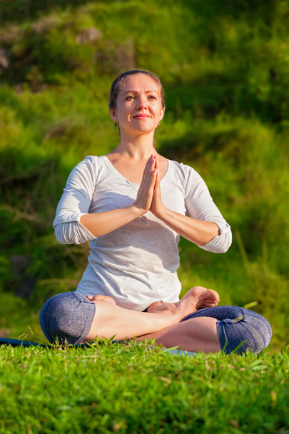 Joven mujer en forma deportiva haciendo yoga Lotus pose al aire libre - Foto, imagen