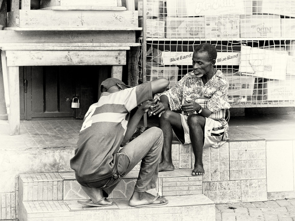 A Ghanaian man cuts the nails of an old man - 写真・画像