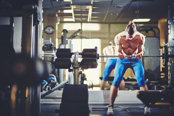 Homme sportif soulevant le poids dans la salle de gym
  - Photo, image