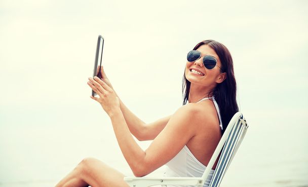 smiling woman with tablet pc sunbathing on beach - Fotoğraf, Görsel