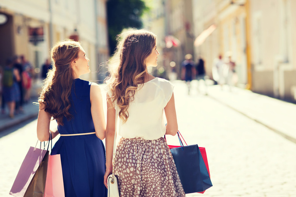 happy women with shopping bags walking in city - Foto, afbeelding