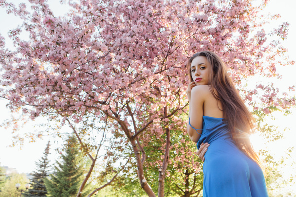 Beautiful young woman standing near the apple tree. - 写真・画像