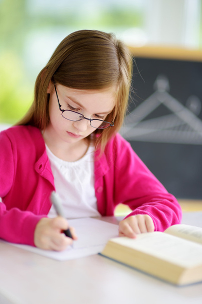 Smart little schoolgirl writing test  - Fotó, kép
