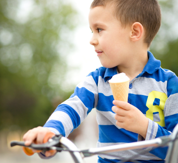 Boy is eating ice-cream while sitting on bike - Photo, Image