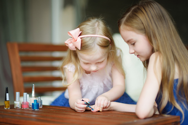 Adorable little girls painting nails - 写真・画像