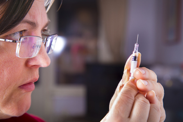 Ruiskua injektiota varten valmisteleva aikuinen nainen
 - Valokuva, kuva