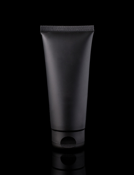 Tubo cosmético negro, fotografía de estudio de tubo de plástico negro para crema, aislado sobre fondo negro
 - Foto, imagen