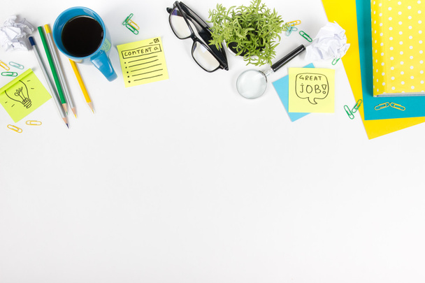Escritorio de mesa de oficina con suministros verdes, bloc de notas en blanco, taza, bolígrafo, vasos, papel arrugado, lupa, flor sobre fondo blanco. Vista superior
 - Foto, Imagen