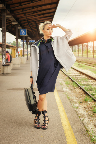 Elegant woman with suitcase posing on the railway station - Фото, изображение