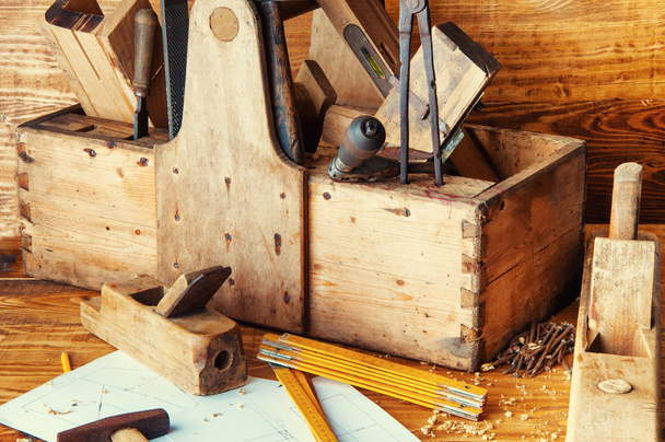 Плотник оборудования на деревянном столе с планами
 - Фото, изображение
