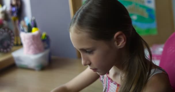 保育園でデスクでゲーム スマート フォンで座っている小さな笑顔の女子高生 - 映像、動画