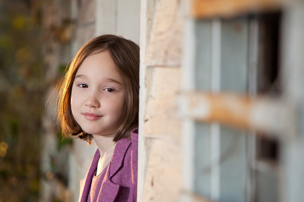 A beautiful young girl peeking out from a house - Photo, Image
