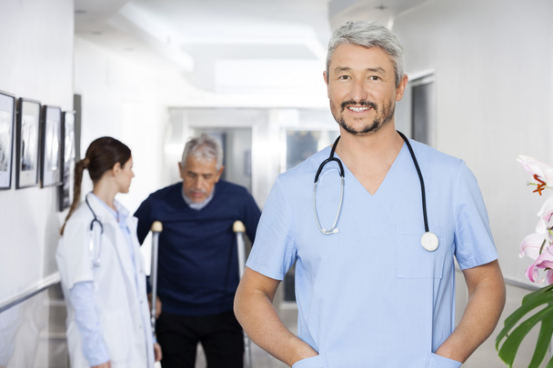 Доктор руками в кишенях стоїть з колегою і пацієнтом
 - Фото, зображення