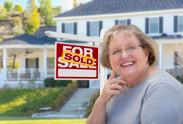 Mujer adulta mayor frente al cartel de bienes raíces, Casa
 - Foto, imagen