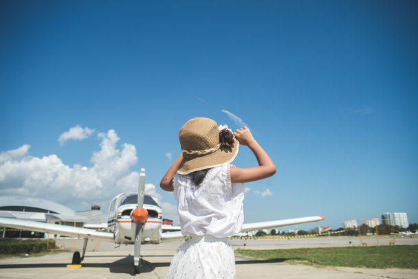 Back side of girl looking at the the sky with small plane backgr - Fotoğraf, Görsel