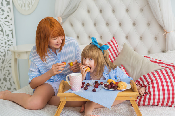 Mother looks at little daughter how she eats - Foto, Bild