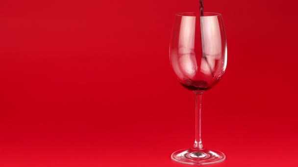 Kırmızı şarap cam içine kırmızı zemin üzerine dökülür. - Video, Çekim