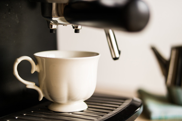 еспресо-машина, що робить каву і наливає в білу чашку
 - Фото, зображення