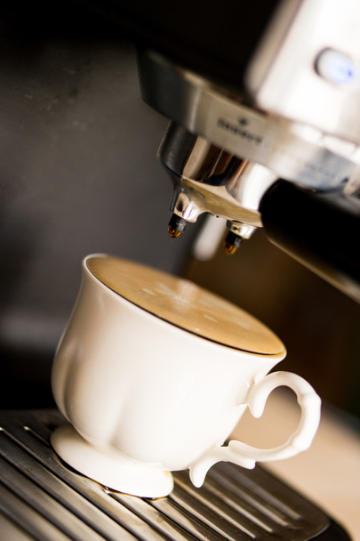 Espressomaschine, die Kaffee zubereitet und in eine weiße Tasse gießt - Foto, Bild