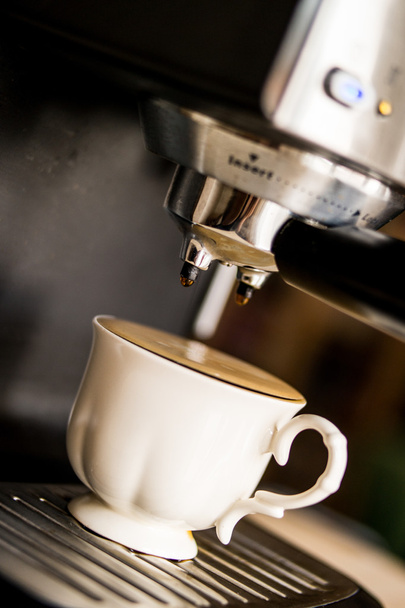 kávéfőző, kávét, és öntött a fehér csészében - Fotó, kép