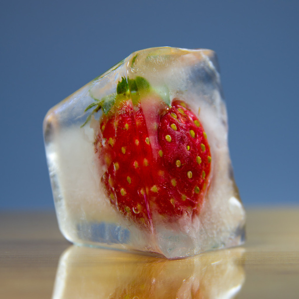 Frozen strawberries in a block of ice on a wooden surface - Photo, Image