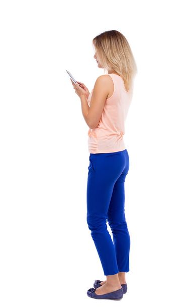 back view of standing young beautiful  woman  and using a mobile - Foto, Imagen