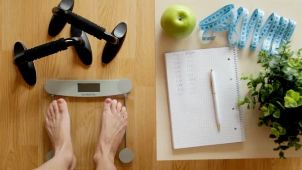 Fitnesz és testsúlykontroll veszteség koncepció, a skála és a notebook egy fából készült asztal - Felvétel, videó