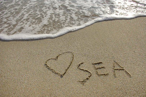 Coração desenhado na areia com seafoam e onda
 - Foto, Imagem