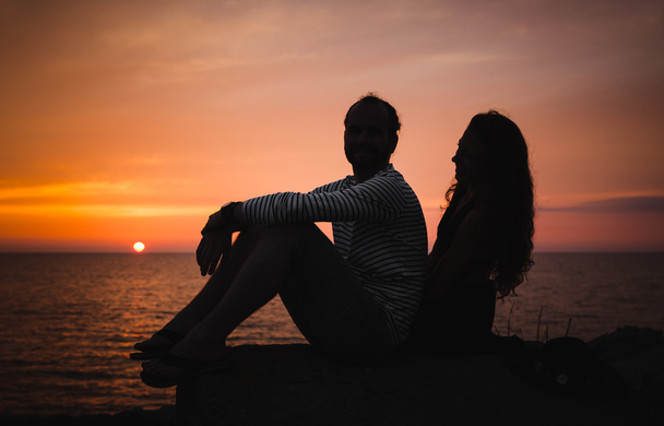 Jovem casal apaixonado contra o pôr do sol no mar
 - Foto, Imagem