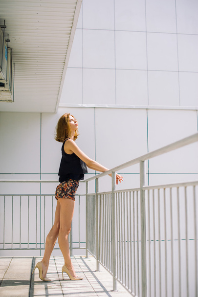 beautiful slim girl in shorts and t-shirt standing on bolkone looking into the distance - 写真・画像