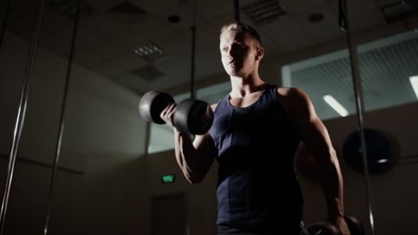 Athletic man pumping biceps with dumbbell in gym - Filmagem, Vídeo