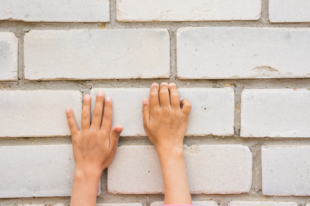 Mano dei bambini cercando di afferrare le schede muro di mattoni
 - Foto, immagini