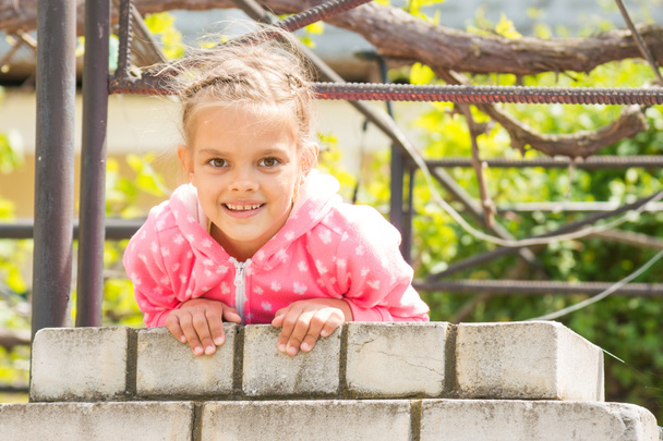 Сім років щаслива дівчина висить на паркан цегли і подивився у кадрі - Фото, зображення