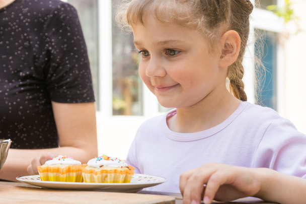 Happy girl is preparing to eat Easter cupcakes - Фото, изображение