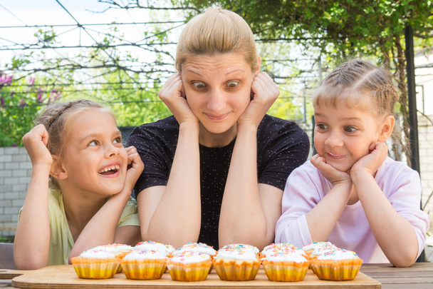 Madre y dos hijas divirtiéndose y mirando cupcakes de Pascua
 - Foto, Imagen
