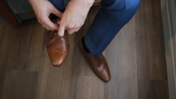 ein junger Mann bindet elegante Schuhe drinnen, aus nächster Nähe - Filmmaterial, Video