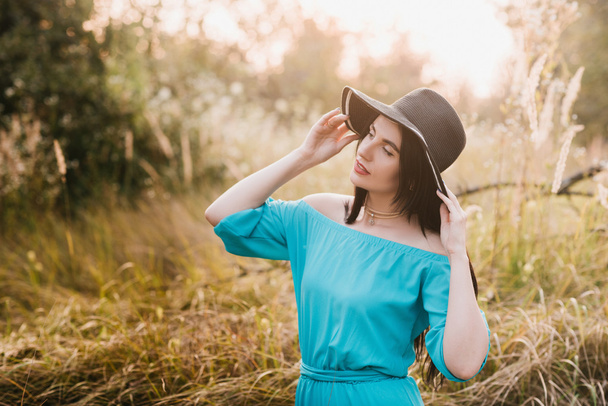 Πορτρέτο του ένα όμορφο κορίτσι σε ένα καπέλο σε ένα πεδίο στο φως του ηλιοβασιλέματος - Φωτογραφία, εικόνα