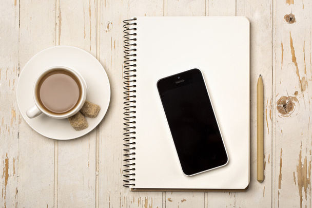 Bovenaanzicht kopje koffie, een laptop van gerecycleerd papier en apparaat op een houten tafel - Foto, afbeelding