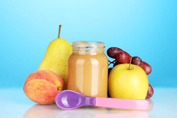 Jar with fruit baby food and spoon on colorful background - Fotografie, Obrázek