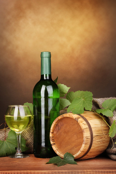 Bottle of great wine with glass and octave on wooden table on brown background - Foto, imagen