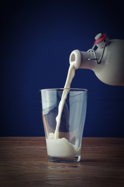 Gegoten melk op houten achtergrond - Foto, afbeelding