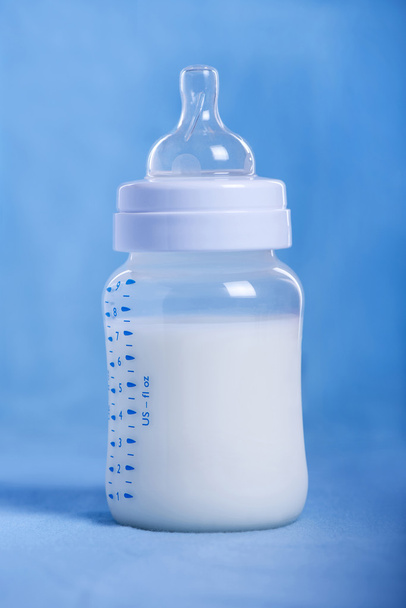Garrafa de leite bebê em um lençol azul
 - Foto, Imagem
