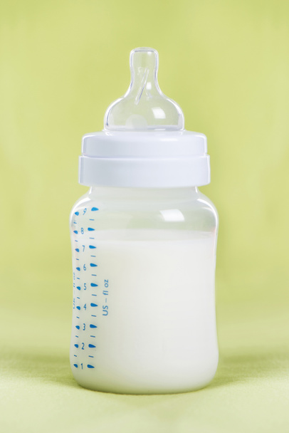 Fles van de melk van de baby op een groen blad - Foto, afbeelding