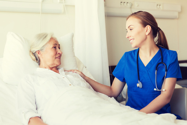 γιατρός ή νοσηλεύτρια που επισκέπτεται ηλικιωμένη γυναίκα στο νοσοκομείο - Φωτογραφία, εικόνα
