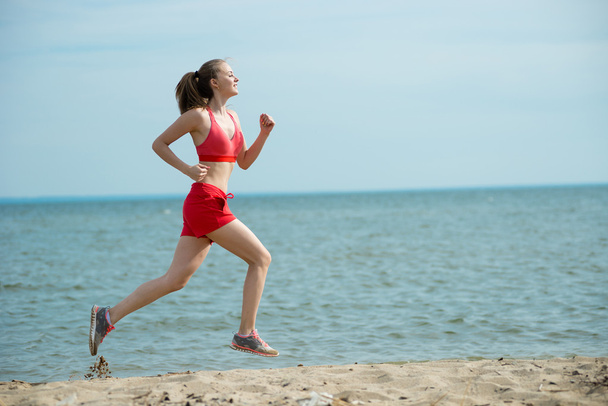 Молода леді біжить на сонячному літньому піщаному пляжі. Тренування. Джог
 - Фото, зображення