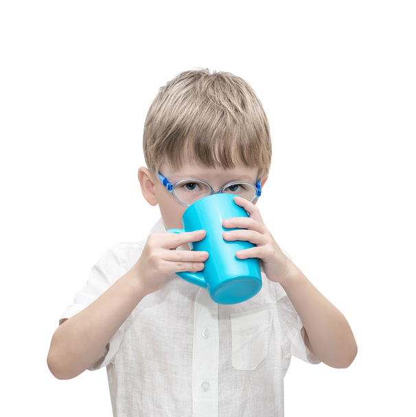 The five-year-old boy wearing spectacles drinks from a mug - Foto, immagini