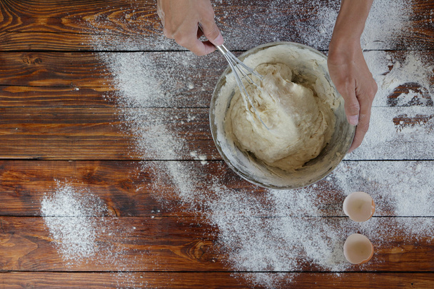 Woman's hands on the wooden table mixing the dough - Photo, Image