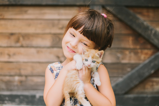 iloinen pieni tyttö, jolla on kissa sylissään
 - Valokuva, kuva