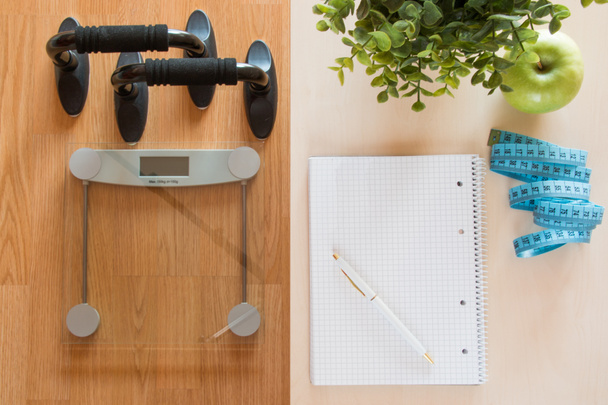 Concepto de fitness y pérdida de peso, báscula y cuaderno en una mesa de madera, vista superior
 - Foto, imagen